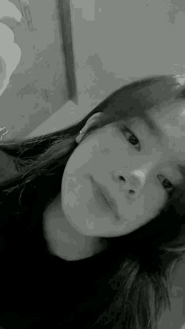 a young girl is taking a selfie in a black and white photo .