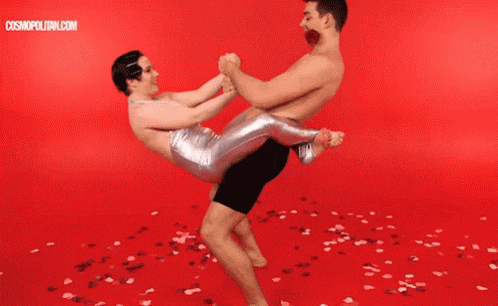 a man is holding a woman in his arms on a red floor .