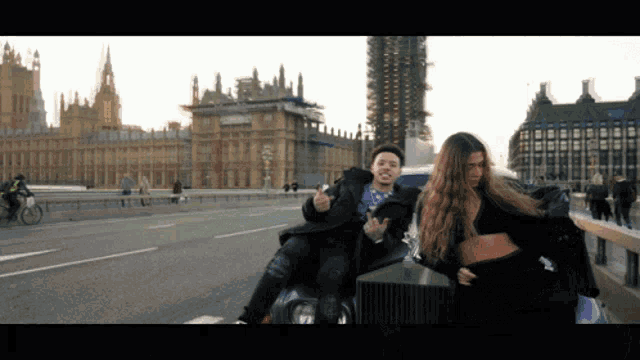 a man and a woman are riding on the back of a rolls royce on a bridge