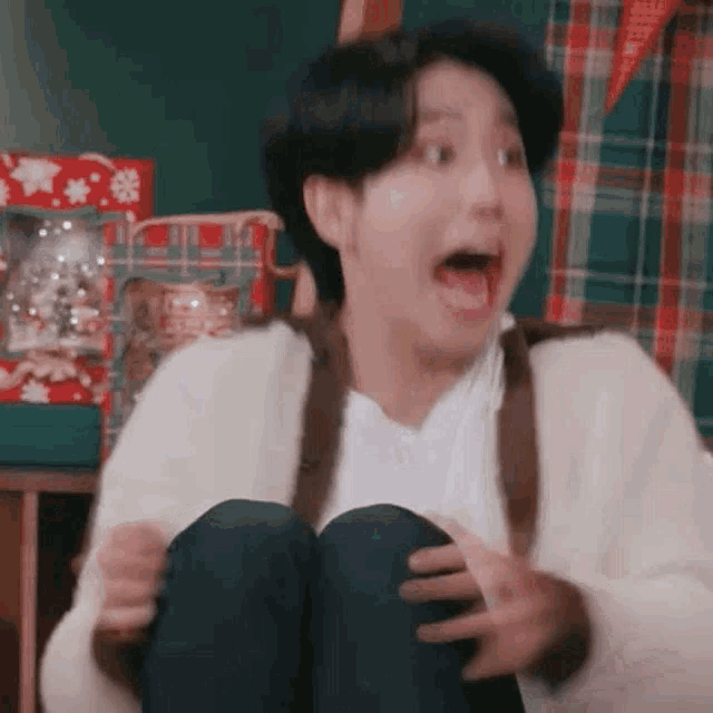a young man is sitting on the floor with his mouth open and making a funny face .