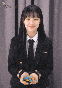 a girl in a suit and tie is smiling and holding something in her hands with the word ivyclub behind her