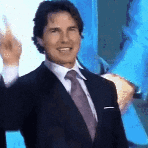a man in a suit and tie is smiling and giving the middle finger .