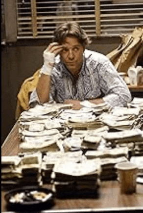 a man with a bandage on his hand is sitting at a table with stacks of money