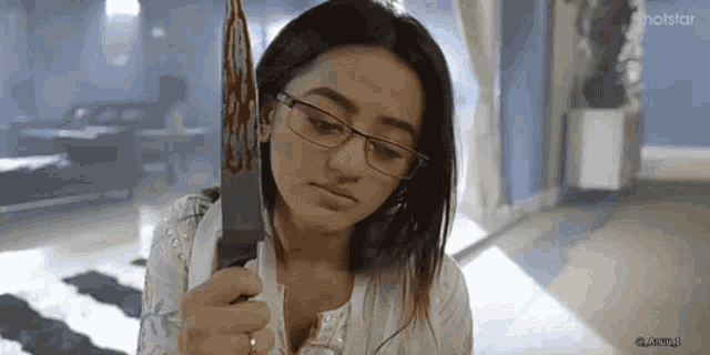 a woman with glasses is holding a knife in her hand