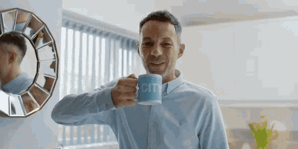 a man in a blue shirt is holding a mug that says city on it