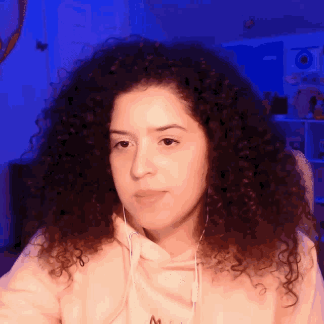 a woman with curly hair is wearing headphones and a pink hoodie