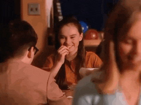 a group of people are sitting at a table eating food and talking .