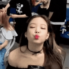 a woman is blowing a kiss with her eyes closed