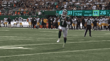 a football player in a green jersey with the number 7 on it is running on the field