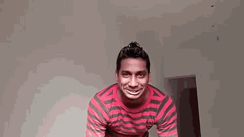 a man in a red and grey striped shirt is holding his hands together