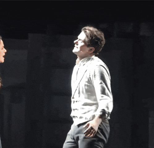 a man in a white shirt is making a funny face on a stage