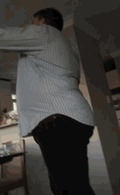 a man in a striped shirt and black pants is standing in a kitchen