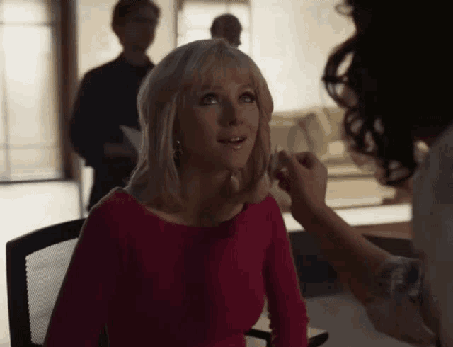 a woman in a pink top is sitting in a chair