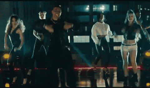 a group of people are dancing in a dark room with smoke coming out of them .