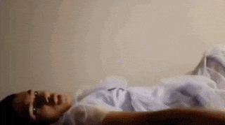 a person is laying on their stomach on a bed with their eyes closed .