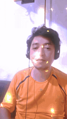 a man wearing headphones and an adidas shirt looks at the camera
