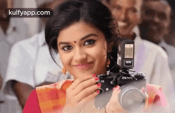 a woman is holding a zenith camera and smiling