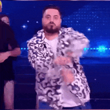 a man with a beard is dancing on a stage in front of a crowd .