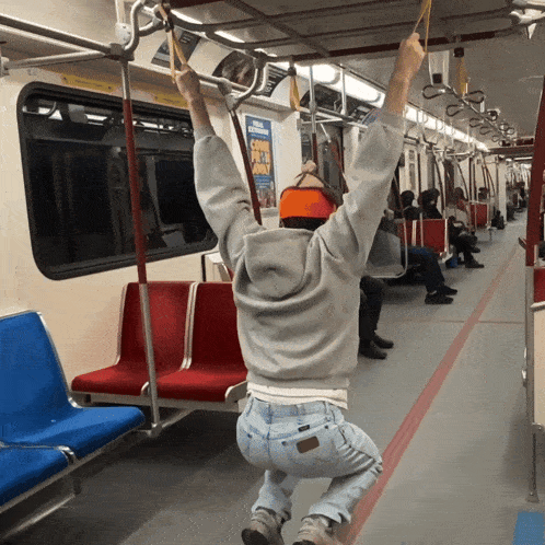 a man is hanging from the ceiling of a subway car with a sign that says ' spike lee ' on it
