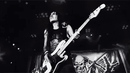a black and white photo of a man playing a guitar on a stage .