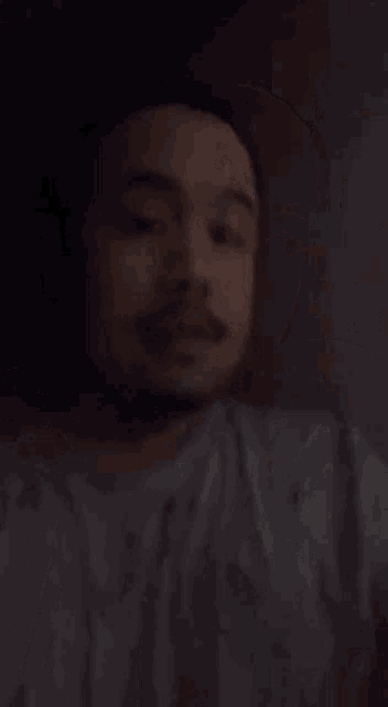a blurry picture of a man with a beard sleeping in a dark room .