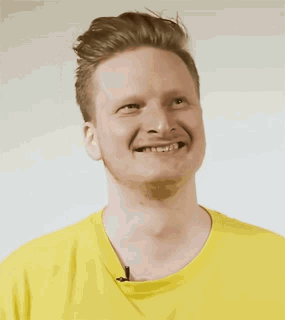 a man wearing a yellow shirt is making a funny face .