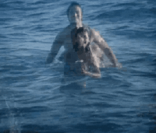 a man and a woman are swimming in the ocean with their arms in the air