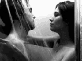 a man and a woman are taking a shower together and looking at each other .
