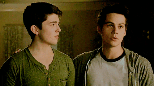 two young men are standing next to each other in a dark room and looking at each other .