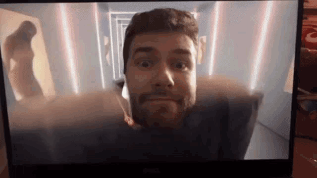 a man with a beard is looking at the camera on a dell monitor