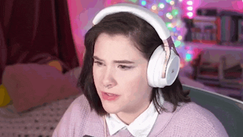 a woman wearing headphones and a pink sweater is making a face .