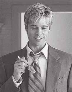 a man in a suit and tie is smoking a cigarette and smiling .