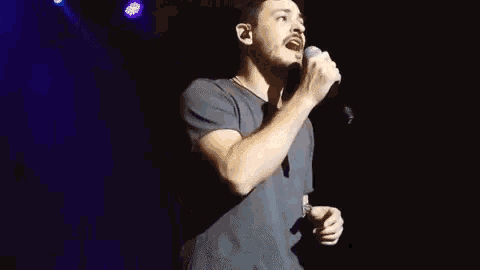 a man singing into a microphone on a stage .