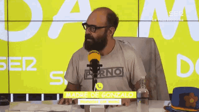 a man with a beard is sitting in front of a microphone with the name madre de gonzalo on the bottom