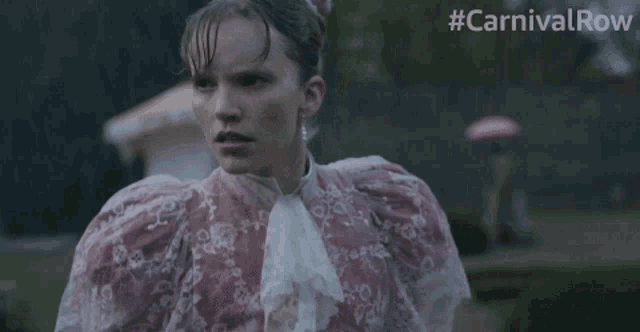 a woman in a pink dress with a feather on her head is standing in front of a sign that says #carnivalrow