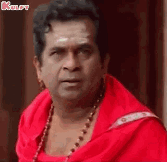 a man is wearing a red shirt and a necklace .