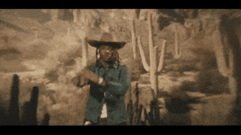 a man in a cowboy hat is standing in front of a desert scene