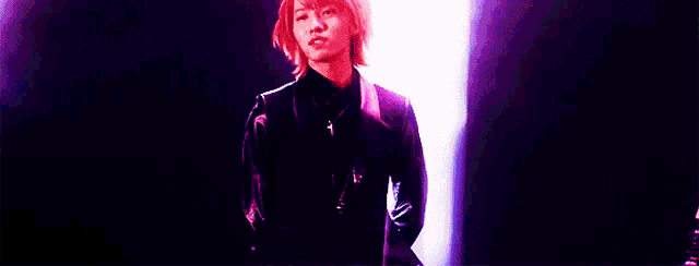 a woman with red hair is standing in front of a blue light with her hands crossed .