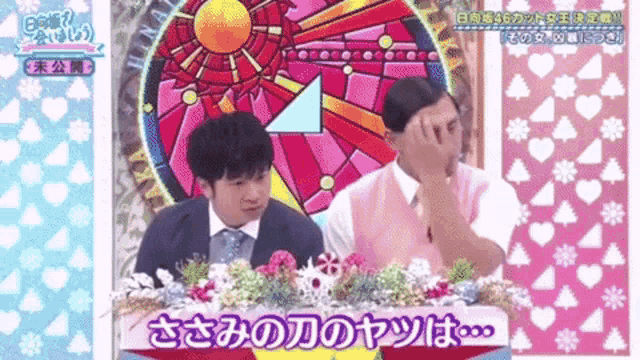 two men are sitting at a table with flowers in front of a stained glass clock .