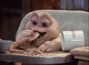 a stuffed animal is sitting in a high chair eating a piece of food .