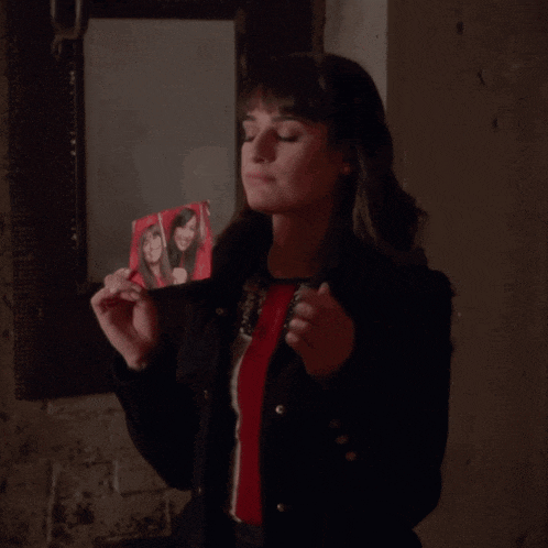 a woman wearing a black jacket with gold buttons is looking at the camera