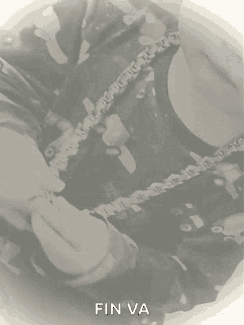 a black and white photo of a person holding a chain with fin va written on the bottom
