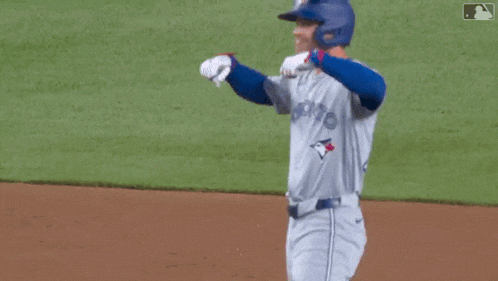a man wearing a blue jays jersey is standing on a baseball field
