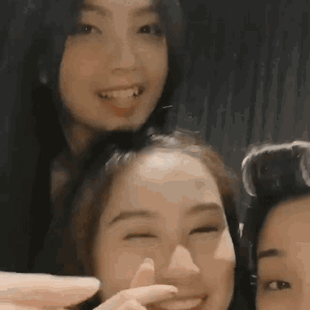 three women are posing for a picture together and one of them is smiling