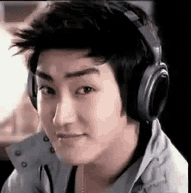 a young man wearing headphones is smiling and looking at the camera .