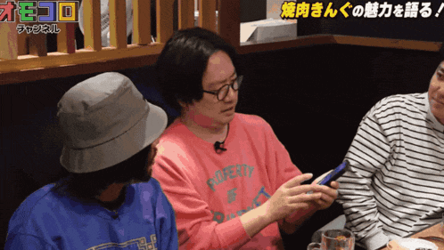 a man wearing a pink shirt that says poverty looks at his phone