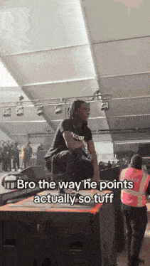 a man with dreadlocks is sitting on a stage with a caption that says bro the way he points actually so tuff