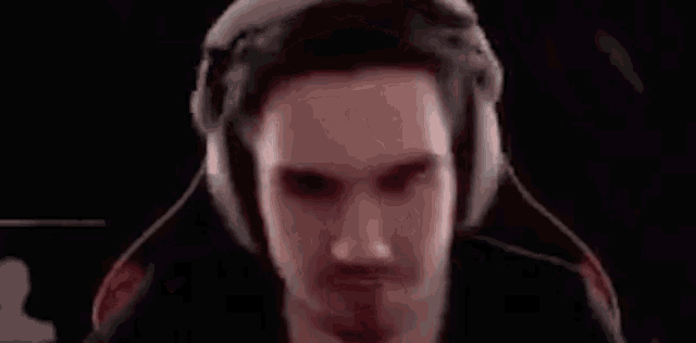 a man is wearing headphones and making a funny face while sitting in a chair .