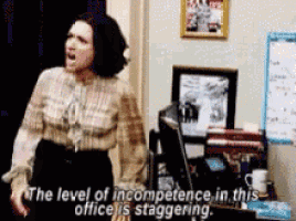 a woman is standing in front of a desk saying the level of incompetence in this office is staggering .