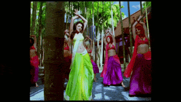 a woman in a green dress is dancing in front of a group of dancers